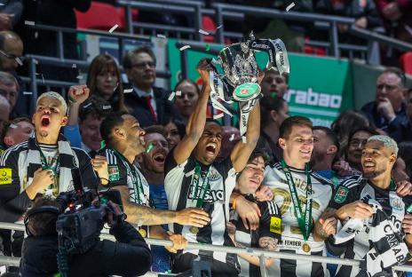 Newcastle United players celebrating with the Carabao Cup trophy.