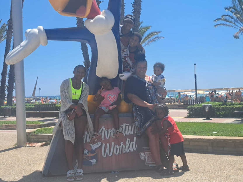 Family posing with a large cartoon bird statue at an amusement park.