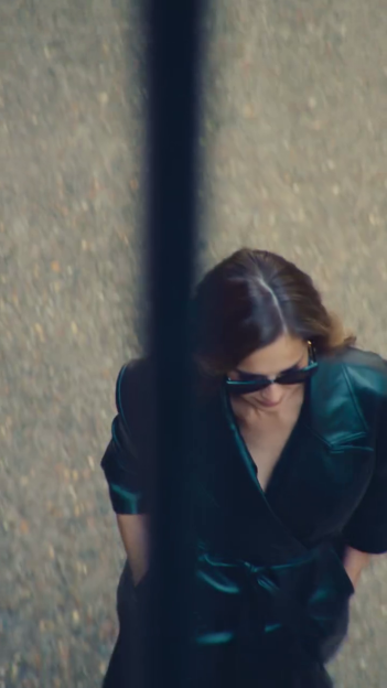 Cheryl in a dark green dress and sunglasses.