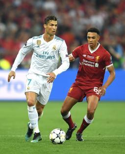 Cristiano Ronaldo of Real Madrid dribbling the ball under pressure from Trent Alexander-Arnold of Liverpool.