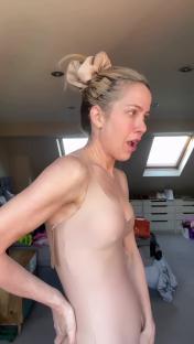 Kate Lawler reacting to a wardrobe malfunction while wearing a nude bodysuit.