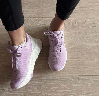Pair of lavender athletic shoes on a wood floor.