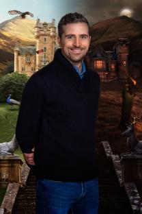 Alexander, a contestant on The Traitors, in front of a castle.