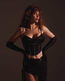 Portrait of Rusya Danilkina, a Ukrainian soldier who lost her leg in combat, wearing a black corset and long gloves.