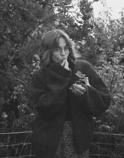 Woman holding a small plant, looking thoughtful.