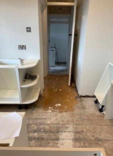 A messy building site with exposed floorboards and incomplete cabinetry.