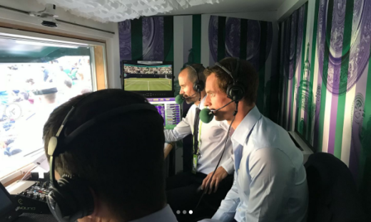 Three commentators in a broadcast booth during a tennis match.