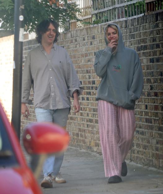 Billie Piper and Johnny Lloyd walking down a street.