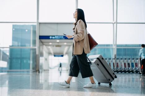 Woman pulling suitcase through airport terminal.