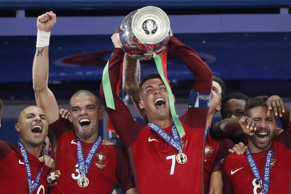 Cristiano Ronaldo lifting the Euro 2016 trophy with Pepe, Ricardo Quaresma, and Joao Moutinho celebrating.