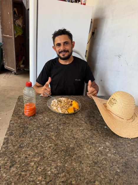 Reinaldo da Silva Melo, an influencer known as "King of Juquira", seated at a table with a meal, giving a thumbs up.