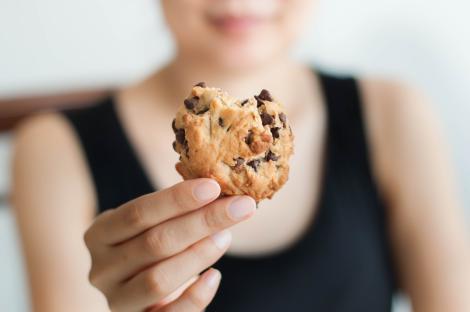 Close-up of a woman holding a chocolate chip cookie.