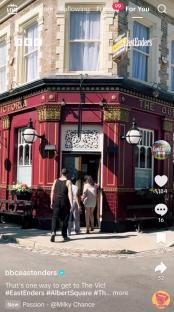 The Queen Victoria pub in Albert Square, London, with people walking past.