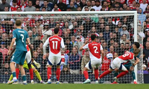A soccer player scoring a goal in front of a crowd.