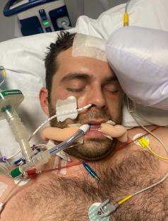Man in hospital bed with medical equipment attached.