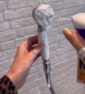 A shower head covered in cleaning foam.