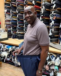 Man holding up loose pants in a fabric store.