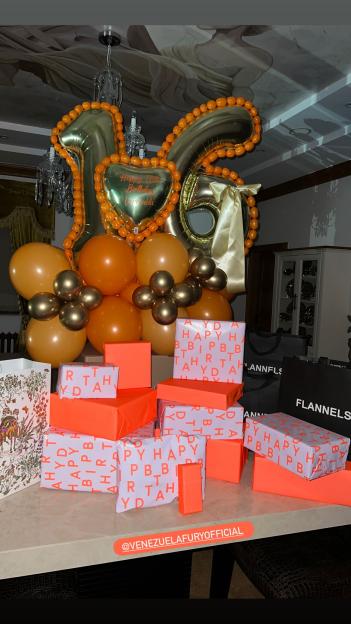 A display of balloons, including large gold "1" and "6" balloons, and multiple wrapped presents, some with "HAPPY BIRTHDAY" lettering.