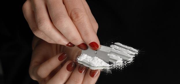 Close-up of hands preparing cocaine for use.
