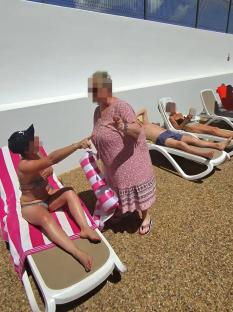Screenshot of a video showing a woman arguing with a couple over sunbeds at a poolside.