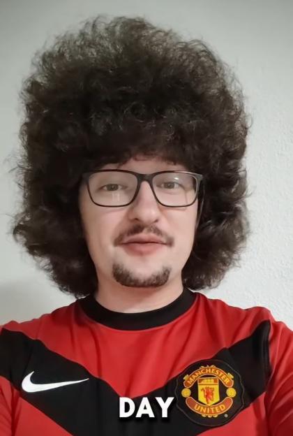 Frank Ilett, a Manchester United fan, wearing a red Manchester United jersey and sporting an afro hairstyle with glasses.
