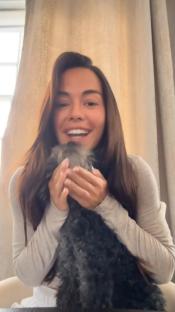 Woman holding a small dark-colored dog.