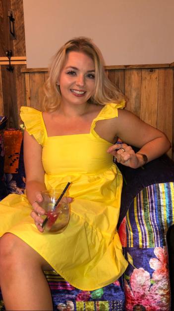 Woman in yellow dress holding a drink.