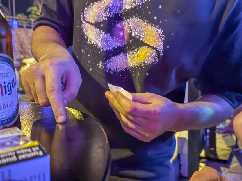 Person's hands handling a small amount of white powder on a bar top.