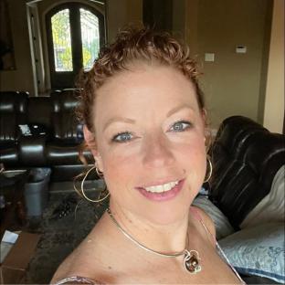 a woman wearing a necklace and hoop earrings smiles for the camera
