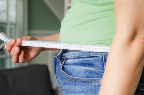 Woman measuring her waist with a tape measure.