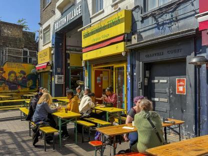 Patrons sitting at outdoor tables in Brixton Village market.