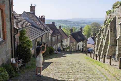 A tourist taking a picture of Gold Hill in Shaftesbury, England.