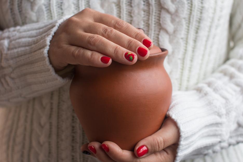 Woman's hands holding a clay pot.