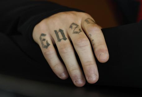 Close-up of a hand with tattoos on the fingers.
