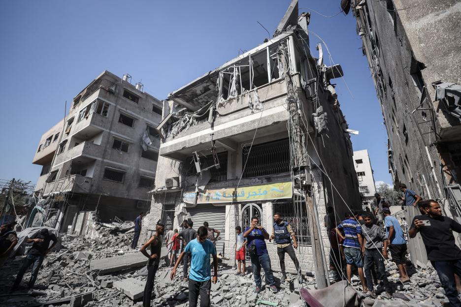 Palestinians conducting search and rescue operations in an area targeted by an Israeli army attack, with destroyed buildings and rubble visible.