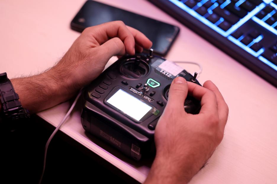 Hands operating a drone controller.