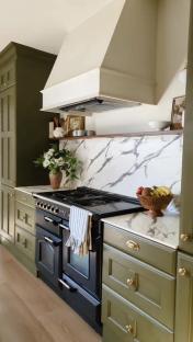 A £50 kitchen with green cabinets, marble countertops, and a black range.