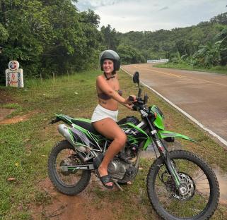 Young woman sitting on a green motorcycle in Thailand.