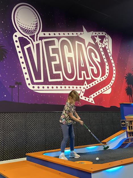 Girl playing miniature golf.