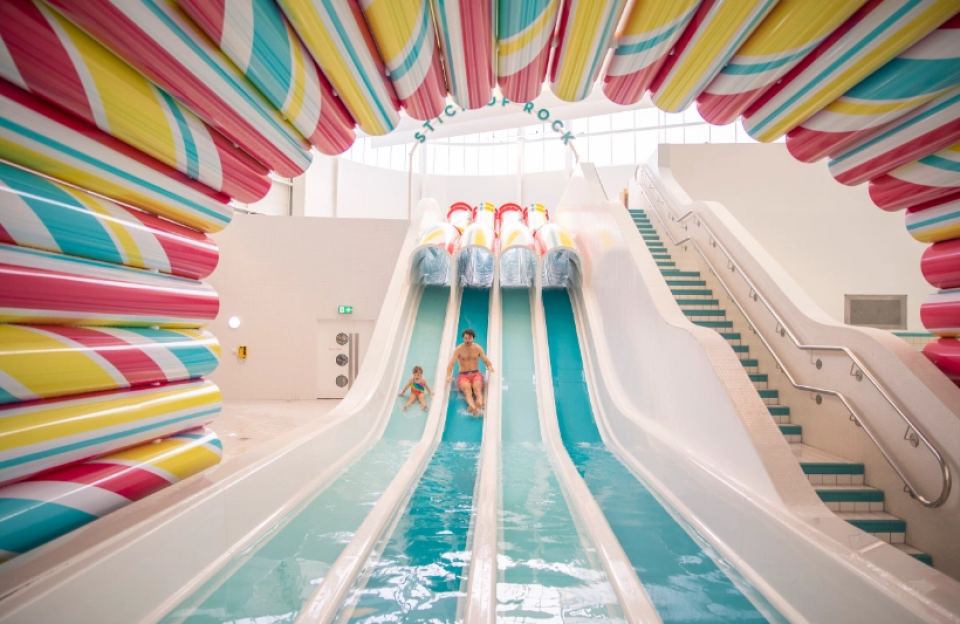 Three water slides in a brightly colored indoor water park.