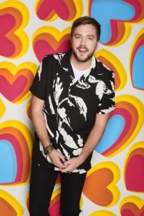 Iain Stirling in front of a heart-shaped background.