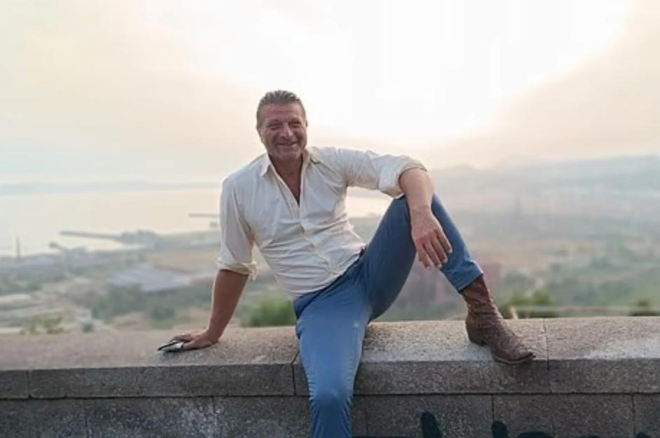 Luigi Di Sarno, 52, sitting on a wall overlooking a city.