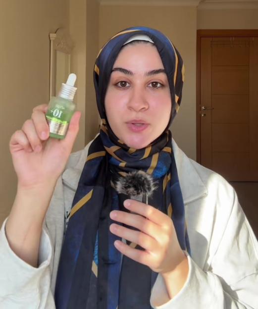 Woman holding skincare serum and recommending it.