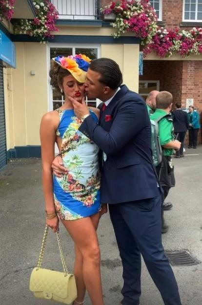 Woman in floral dress kissed by man in suit.