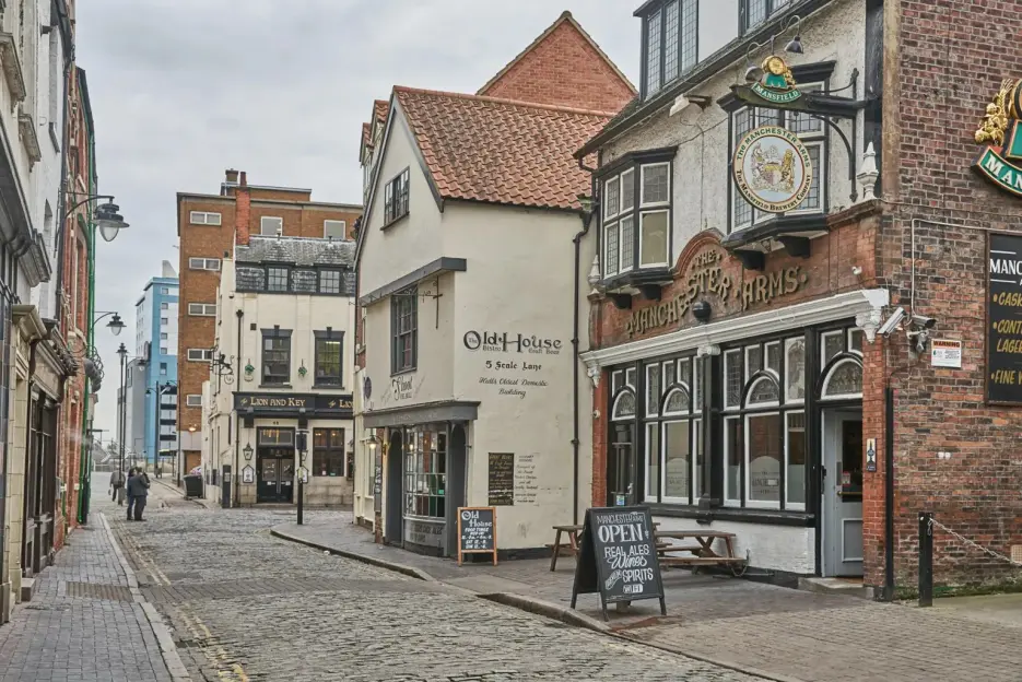A street scene with the Old House Pub and the Manchester Arms, two historic pubs, on a cobblestone lane in Hull.