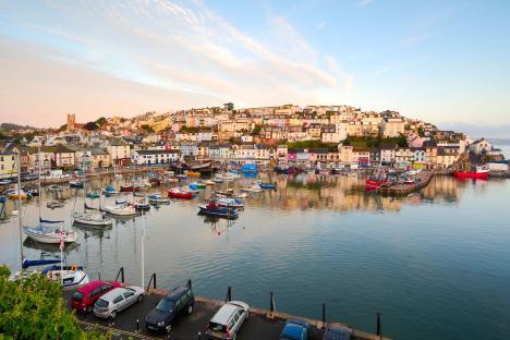 Sunrise view of Brixham harbor, a small fishing town in South Devon, with colorful houses and many boats.