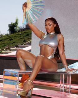 Megan Thee Stallion in a silver swimsuit holding a iridescent hand fan.