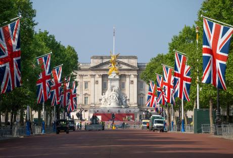 Early morning view of The Mall in London, UK, with Union Jack flags lining the street and Buckingham Palace in the background.