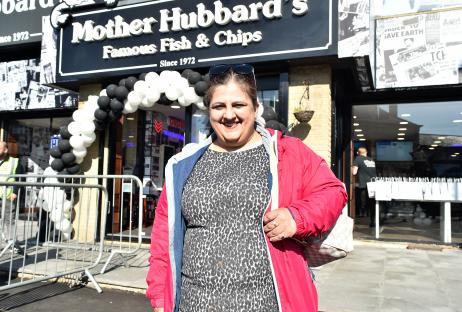 Two women holding Mother Hubbard's fish and chips bags outside the shop.