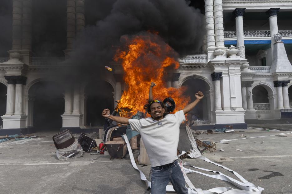 A man celebrates in front of a burning building during a protest in Kathmandu, Nepal.